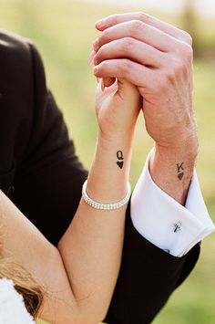 a bride and groom holding hands with tattoos on their wrist