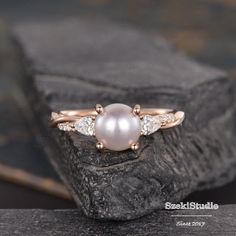 a pearl and diamond ring sitting on top of a rock