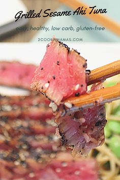 the chopsticks are being held up to eat some meat and vegetables on the plate