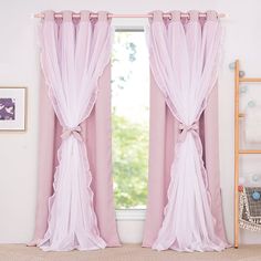 pink curtains with ruffles and bows hanging in front of a window