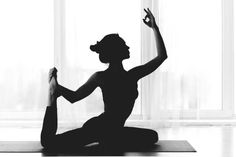 a woman doing yoga in front of a window with her hands up to the side