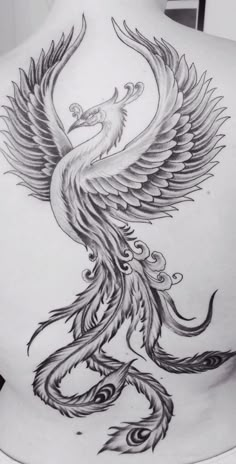 the back of a woman's body with a tattoo design on it, depicting a bird