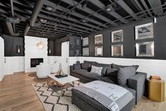 a living room with black and white decor on the walls, wood flooring and exposed ceilings