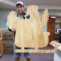 a man holding up a wooden cut out of a cat