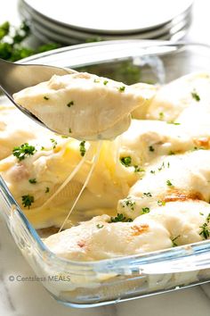 a glass casserole dish with chicken and cheese being lifted from the casserole