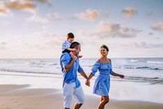 a man and woman are walking on the beach with their child in his arms as they hold hands