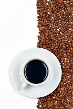 a cup of coffee sitting on top of a pile of coffee beans