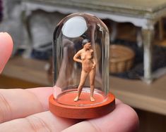 a miniature figurine in a glass dome on top of a wooden base is shown