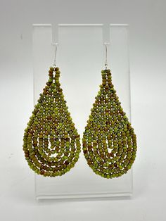 Check out these stunning Modern Style Handwoven Tear Drop Earrings with Small Olive Green with hints of Brown Glass Sead Beads  Each bead is meticulously selected and woven together to create a unique design. Because they're handwoven, every pair is one-of-a-kind, and any small imperfections only add to their charm! I absolutely adore crafting each pair and selecting vibrant colors and intricate beading stitches. Sterling Silver Dangle Posts .. mini 925 stamp on the dangle post (see photo)  Comfortable & Lightweight  IMPORTANT: Color may vary in photos and on your screen  Please view the photo with ruler & quarters for length (not included)  Bead Size:  11 Do NOT get wet, pull or tug or coat with hairspray Earrings created with glass seed beads, beading thread and dangle posts Beading Stitches, Native Crafts, Intricate Beading, Beading Thread, Tear Drop Earrings, Nativity Crafts, Love Craft, Glass Seed Beads, Seed Bead Earrings