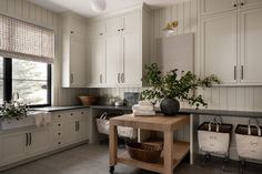 a kitchen filled with lots of white cupboards and counter top next to a window