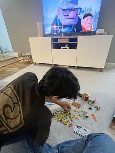 a young boy playing with legos on the floor in front of a flat screen tv