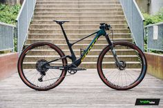 a bike parked on top of a wooden floor next to stairs and railings with trees in the background