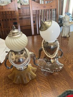 two glass and metal lamps sitting on top of a wooden table