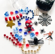 various toys and decorations are laid out on a white surface, including spider - man brooches