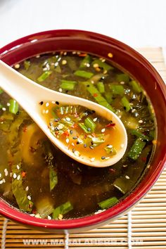 a spoon full of soup with green beans and sesame seeds