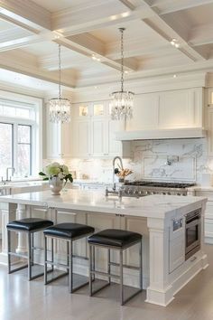 a large kitchen with white cabinets and marble counter tops, two stools at the island