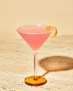 a pink cocktail with an orange slice on the rim