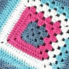 a crocheted blanket with pink, blue and white squares on top of it