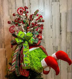 a christmas wreath with candy canes and green grass in front of a wooden wall