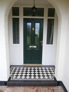 a black and white checkered floor in front of a green door with two sidelights