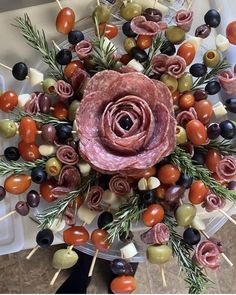 an arrangement of meat and olives on skewers, arranged in the shape of a flower