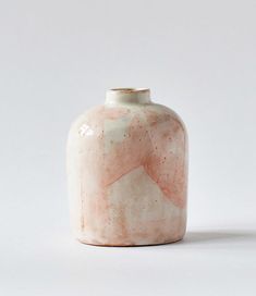 a white and pink vase sitting on top of a table