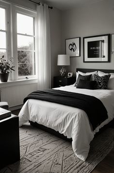 black and white bedroom with large bed, two windows and pictures on the wall above it