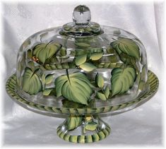 a glass covered dish with green leaves on it