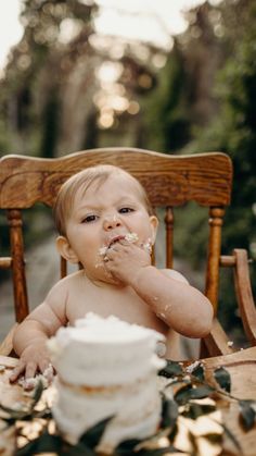 a baby sitting in a chair eating cake