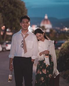 a man and woman are walking down the street holding wine bottles in their hands while smiling at each other