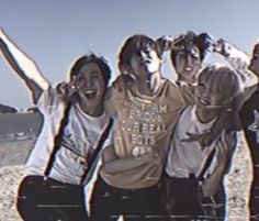 a group of young men standing next to each other on top of a sandy beach