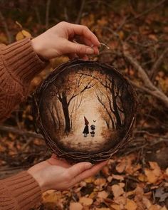 two people holding up a paper plate with an image of trees in the woods on it