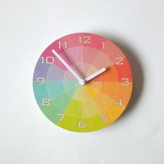 a clock that is on the wall with color wheel in it's center and hands