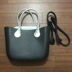 a black and white purse sitting on top of a wooden floor next to a charger