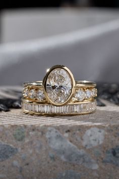 two gold wedding rings sitting on top of each other next to another ring with a diamond in the middle