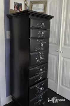 a tall black dresser with flowers painted on it's drawers in a living room