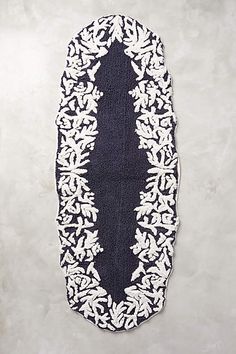 a black and white rug with an oval design on the bottom, in front of a gray wall