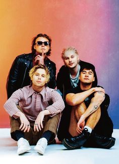 three young men sitting next to each other in front of a colorful wall with the words 5 seconds of summer on it