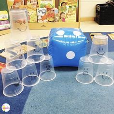 plastic cups with faces drawn on them are lined up in front of a blue cooler