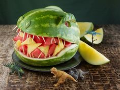 a watermelon sculpture of a dinosaur with its mouth open and teeth wide open