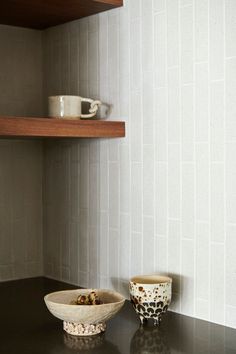 two bowls sitting on top of a black counter next to a shelf filled with dishes