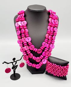 This Caribbean style hot pink mini custom set comes with a necklace and complimentary earrings, and a stretchy bracelet.Necklace - "Barbados Bopper": Brushed in a colorful finish, rows of vivacious pink wooden beads and discs are threaded along shiny brown cording for a summery look. Features a button loop closure. Includes one pair of matching earrings. Bracelet - "Island Expression": Painted in a flamboyant Pink Peacock finish, round wooden beads are threaded along stretchy bands that weave in Adjustable Pink Jewelry With Wooden Beads, Pink Wooden Beads For Gifts, Cheap Pink Multi-strand Beaded Necklaces, Pink Hand-strung Round Beads Necklace, Paparazzi Pink Wood Necklace, Bohemian Multi-strand Pink Necklace, Pink Multi-strand Large Beads, Caribbean Style, Pink Peacock