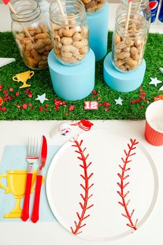 baseball themed desserts are displayed in glass jars on a table with red and blue utensils