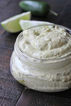 a jar filled with white sauce next to an avocado