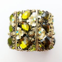 - Stunning chunky hinged bracelet with metal flowers and rhinestones in green and gold colours.  - In excellent condition - looks unused.  - Inside measure: 6.5 cm across. - Width: 5 cm. Delivered First Class, tracked and signed with Royal Mail. Gift wrapping is available, see details. Green Bangle Cuff Bracelet For Party, Vintage Green Bracelets For Party, Elegant Green Crystal Metal Bracelet, Green Costume Jewelry Bracelets For Party, Adjustable Green Crystal Metal Bracelet, Green Metal Bracelets For Costume Jewelry, Elegant Green Metal Cuff Bracelet, Green Jeweled Bangle For Party, Green Metal Flower Jewelry