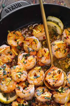 cooked shrimp and lemon in a skillet with a wooden spoon on the side, ready to be eaten