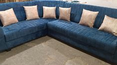 a blue sectional couch with several pillows on it's back and the seat facing outward