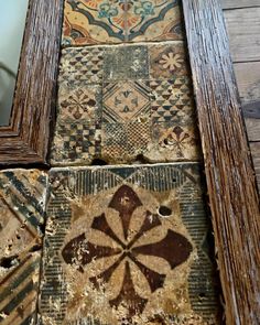 an old wooden frame with decorative tiles on it and a mirror in the corner next to it