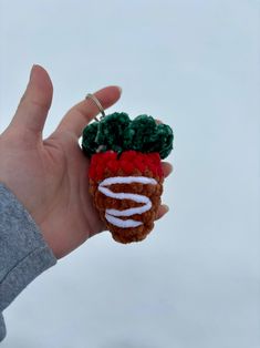 a hand is holding a miniature strawberry ornament in it's left hand