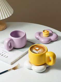 there is a cup of coffee next to a book and a spoon on the table